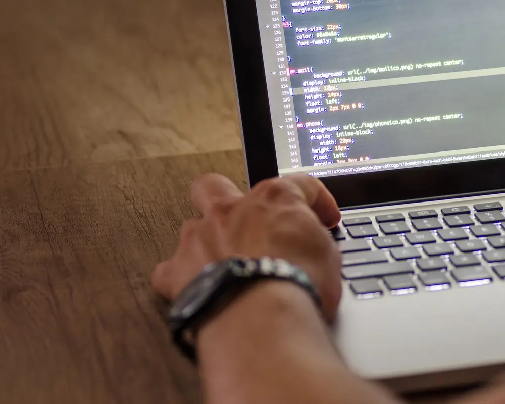 A hand on a laptop showing code
